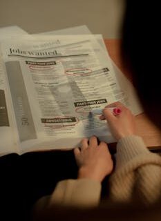 Close-up of a person marking job listings in a newspaper indoors.