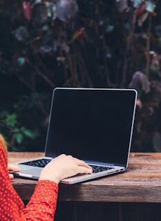 Woman working remotely on a laptop outdoors, showcasing modern digital nomad lifestyle.